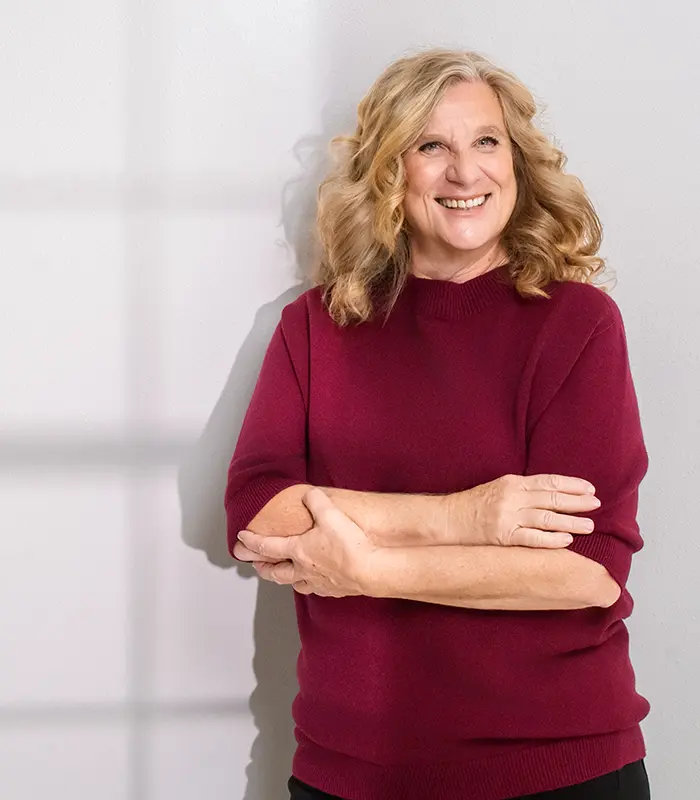 Pädagogin und Elternoach Gabriele Mann (geborene Reichart) lächelt in einem weinroten Pulli für ihr Über mich Foto in die Kamera.