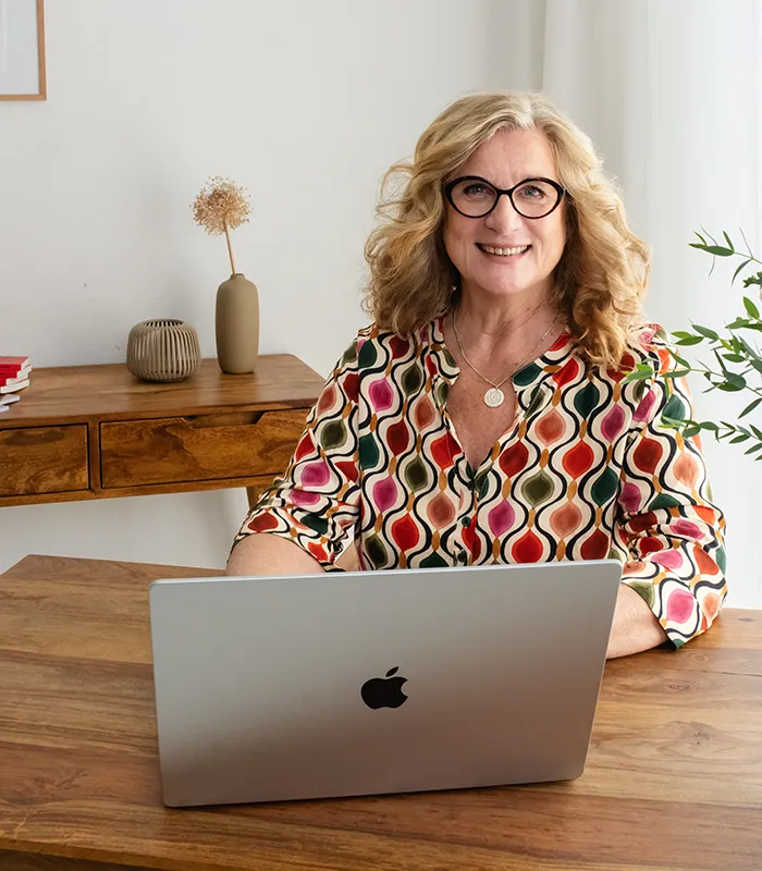 Gabriele Reichart sitzt hinter ihrem Laptop und schreibt ihren Newsletter mit Tipps für ein liebevolles Miteinander.